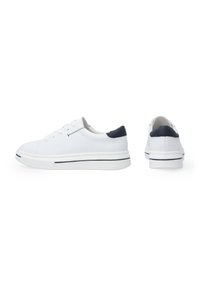 Weiße Sneakers mit einem glatten Obermaterial aus Canvas, navyfarbenen Lederakzenten an der Ferse und einer weißen Gummisohle mit einem schwarzen Streifen.