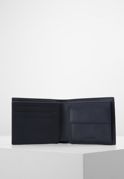 Portefeuille en cuir marine avec plusieurs emplacements pour cartes et un compartiment. Texture lisse, design minimaliste, avec un détail de logo gaufré.