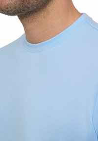 Jasnoniebieska koszulka typu crew-neck wykonana z miękkiej mieszanki bawełny, z bezszwowym kołnierzykiem i gładką fakturą.