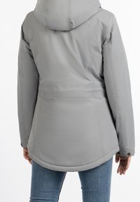 Grå isolerad jacka med huva, med en åtdragen midja, slät textur och kontrasterande sömmar. Mjuk tyg med rundad nederkant.