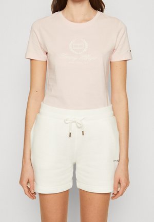 Camiseta de algodón rosa claro con cuello redondo y diseño de logo, combinada con pantalones cortos de forro polar blancos con cintura ajustable con cordón y dobladillo vuelto.