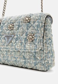 Borsa a mano in tweed azzurro chiaro con una texture trapuntata, decorata con accenti di gemme trasparenti e una placca logo triangolare. Con tracolla a catena.