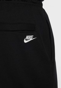 Joggers negros de Nike, hechos de una tela suave, con una cintura elástica, bolsillos laterales y un logo de Nike bordado en el muslo izquierdo.