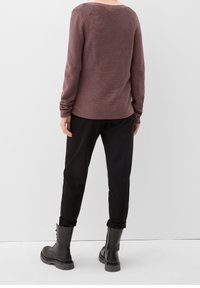 Pull mauve côtelé à manches longues avec un col rond, associé à un pantalon noir et des bottes montantes noires lacées.