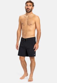 Černé plavky s šňůrkou v pase, bočními kapsami a malým logem na spodní levé straně. Tkanina působí lehce a rychleschnoucí.