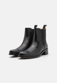 Botas de tobillo de cuero negro con un acabado brillante, paneles laterales elásticos, puntera redonda y un tacón bajo apilado.
