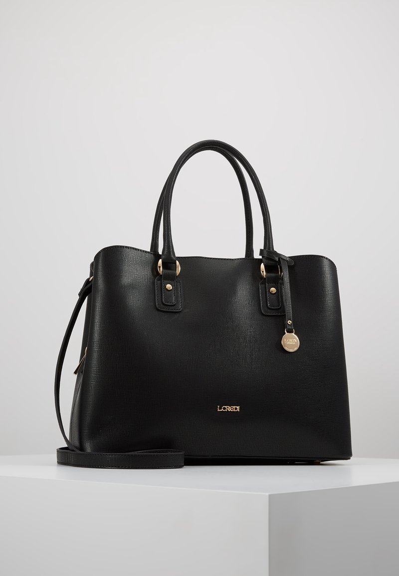 Sac à main en cuir texturé noir avec doubles poignées, une bandoulière amovible, une quincaillerie dorée et un petit charm rond suspendu.