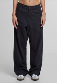 Pantalones de pierna ancha en un intenso color azul marino, confeccionados en algodón. Presentan un cierre de botón, bolsillos frontales y detalles metálicos. Suave textura y costuras ajustadas.