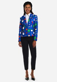 Blue blazer with Christmas patterns, featuring Santa, reindeer, trees, and snowflakes, paired with black pants and pointed shoes.