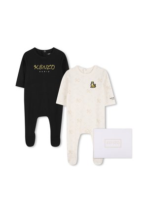 Deux pyjamas bébé avec pieds, un noir avec texte doré "Kenzo Paris", un blanc avec petits imprimés et patch tigre, à côté d'une boîte Kenzo blanche.