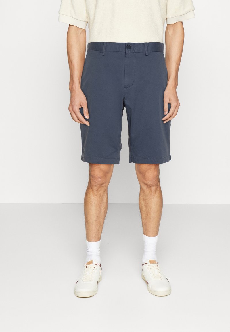 Shorts en coton bleu marine avec fermeture à bouton et passants de ceinture, présentant un design à jambe droite et un tissu légèrement texturé.