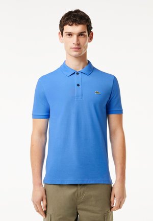 Polo shirt in cotone blu con colletto, tre bottoni e un piccolo logo verde sul petto. Maniche corte e vestibilità standard.