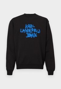 Svart crewneck sweatshirt med lange ermer og blå graffiti-stil tekst "KARL LAGERFELD JEANS" på midten foran.