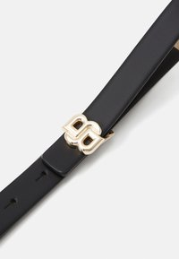 Ceinture en cuir noir avec une boucle double "B" en ton doré, présentant une texture lisse et plusieurs trous d'ajustement le long de la sangle.