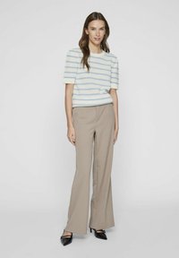 Top de punto a rayas azul claro y blanco con mangas cortas, combinado con pantalones de pierna ancha beige y tacones negros de punta.