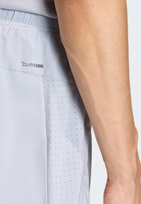 Lys grå treningsshorts med en pustende sidepanel med perforeringer og en "CLIMACOOL"-logo på midjebåndet.