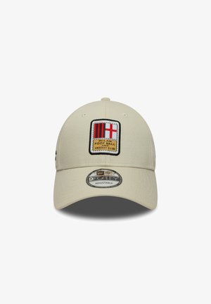 Casquette de baseball beige en tissu, dotée d'un badge brodé avec des rayures rouges et noires et une croix blanche, étiquetée "Milan Football and Cricket Club."