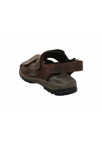 Brown leather sandal with an open design, adjustable strap, and cushioned sole. Features a textured upper and patterned footbed.