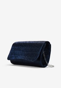 Bolso de mano de terciopelo azul marino con un acabado texturizado, cierre con solapa y una correa de cadena plateada para llevar al hombro. Diseño compacto y rectangular.