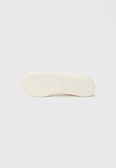 Apavu zole no krēmkrāsas gumijas ar teksturētu virsmu, kurā ir iestrādāti apaļi un trijstūra raksti, nodrošinot saķeri un atbalstu.