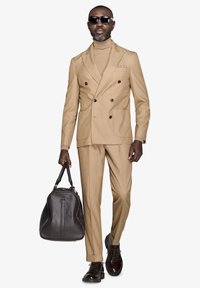 Tan dobbeltbrystet jakkesæt med slim fit, matchende turtleneck, sorte solbriller, brun lædertaske og polerede sko.