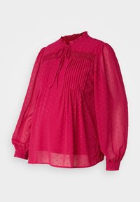 Blouse péplum rose vif, en tissu transparent avec des motifs de points en relief, des plis, un col à volants et des manches longues bouffantes.