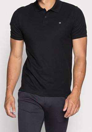 Black polo shirt made of cotton blend with short sleeves, a collar, two-button placket, and a small white logo on the left chest.