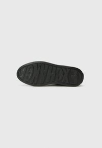 Talpa de sneaker negru, având cauciuc texturat, literele „EXCHANGE” embossate și un profil plat, concepută pentru durabilitate și aderență.