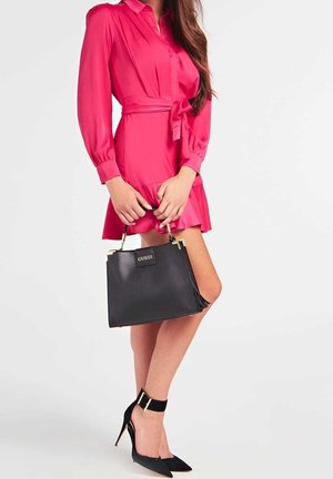 Robe rose avec une ceinture à nouer, sac à main noir texturé avec des accents dorés, et escarpins noirs à brides à la cheville et bouts pointus.