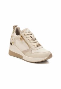 Zapatilla beige con un upper texturizado, diseño de cordones, cremallera lateral y acentos metálicos. Presenta un tacón oculto.