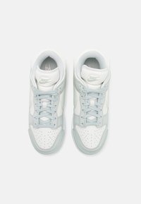 Nike-sneakers med en färgsättning av vitt och ljusblått, gjorda av läder och meshmaterial, med perforerat tåfack och platta snören.