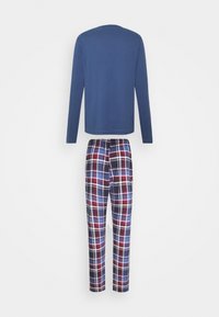 Camisa de manga larga azul marino con escote redondo combinada con pantalones de pijama de cuadros que presentan una combinación de colores en rojo, azul y blanco.