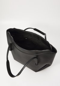 Sac fourre-tout en cuir noir avec fermeture éclair, deux poignées robustes et une texture lisse, doté d'un intérieur spacieux.