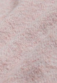 Zacht roze gebreide stof met een gestructureerd oppervlak en subtiele schaduwv variaties, die een gezellige en lichte uitstraling tonen.