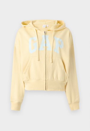 Hanorac galben deschis cu fermoar, buzunare frontale, glugă cu șnur, manșete striate și logo-ul „GAP” mare, alb, pe piept.