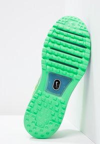 Semelle extérieure en gomme verte avec un motif de grip texturé et des carrés en relief. Comprend une section transparente et un logo Nike noir.