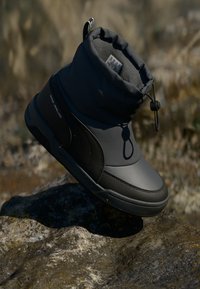 Grijze waterdichte laars met een gewatteerde kraag, elastische sluiting met toggles, rubberen zool en een gladde buitenkant. Heeft een slank, afgerond ontwerp.