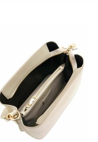 Sac à main beige à la forme structurée, avec une fermeture éclair dorée et deux compartiments. Il comporte un intérieur sombre contrastant et une petite pochette grise.