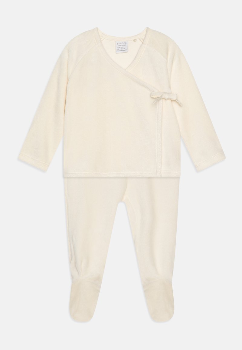 Ensemble de bébé couleur crème, fabriqué dans un tissu doux, avec des manches longues, une fermeture à nouer et un design avec pieds. Texture lisse partout.