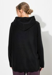 Felpa nera con cappuccio spazioso, maniche lunghe e vestibilità rilassata, realizzata in morbido tessuto con dettagli minimi.