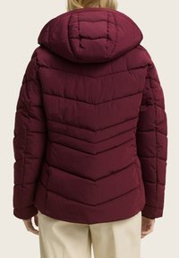 Bordo puffer jakna s chevron uzorkom, koja ima kapuljaču i prošivene detalje. Materijal izgleda mekano i toplo.