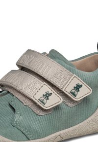 Scarpa verde in velluto a coste per bambini con due strap beige in velcro, ognuno con una piccola icona a forma di coniglietto verde sulla chiusura.