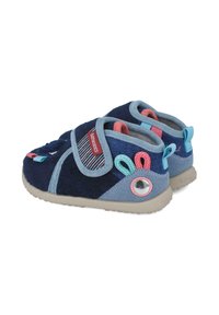 Zapatitos de niño en azul marino con parte superior de tela suave, tira de velcro, acentos coloridos, suela gris y detalle decorativo de ojete en el talón.