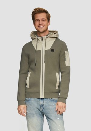 Olivgrüne Kapuzenjacke mit hellbeigen Akzenten, Reißverschluss und Fronttaschen. Verfügt über eine strukturierte Stoffqualität und eine Kordelzugkapuze.