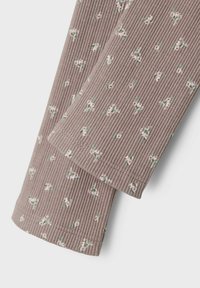 Top in tessuto a coste di un leggero mauve con piccoli fiori bianchi e foglie verdi. Presenta una superficie testurizzata e bordi orlati per una maggiore durata.
