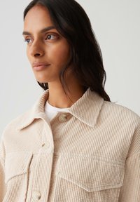 Kordjacke in hellbeige, mit einem kragenähnlichen Hals, zwei vorderen Taschen und Knopfverschlüssen, ausgestattet mit einer strukturierten Ripp-Oberfläche.