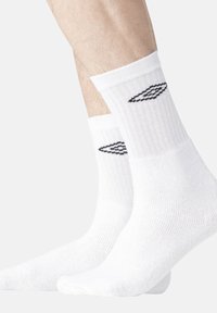 Chaussettes en coton blanches à tige courte avec une texture côtelée et un design graphique noir sur le côté. Matériau doux visible au niveau de la cheville et de la zone du pied.