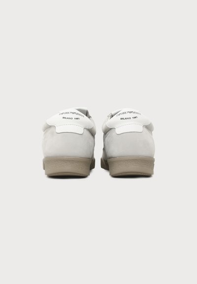 Paire de baskets blanches vues de dos, semelles couleur camel, texte « "Emporio Armani Milano 1981" » sur les languettes du talon.