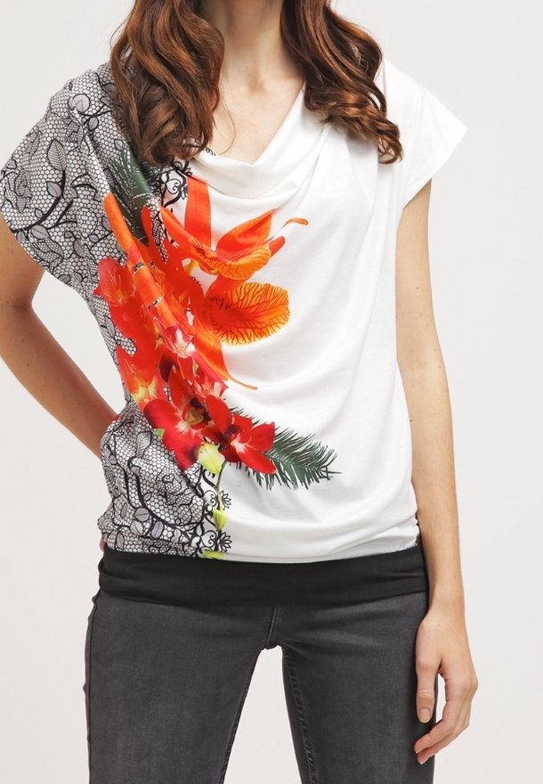 Top blanco con escote drapeado, que presenta un vibrante estampado de flores en naranja y rojo de un lado y un patrón de encaje negro del otro.