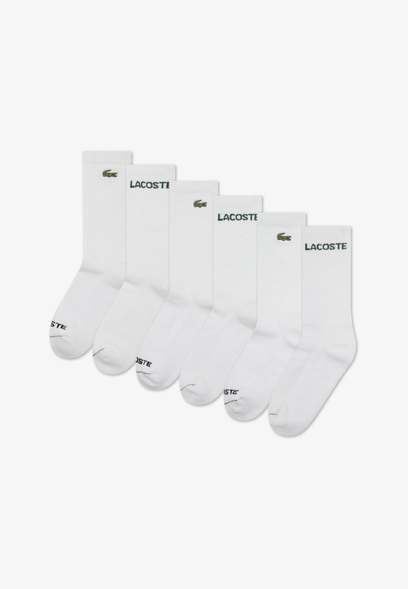 Lot de six chaussettes blanches montantes, arborant un logo crocodile vert brodé et le texte "LACOSTE" sur le bord-côte. Texture côtelée, matière en mélange de coton.